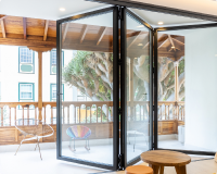 A picture of Cobalt Aluminium's black door product called Bi-Fold Plus. It shows it seperating the environment and unifying the houses space.